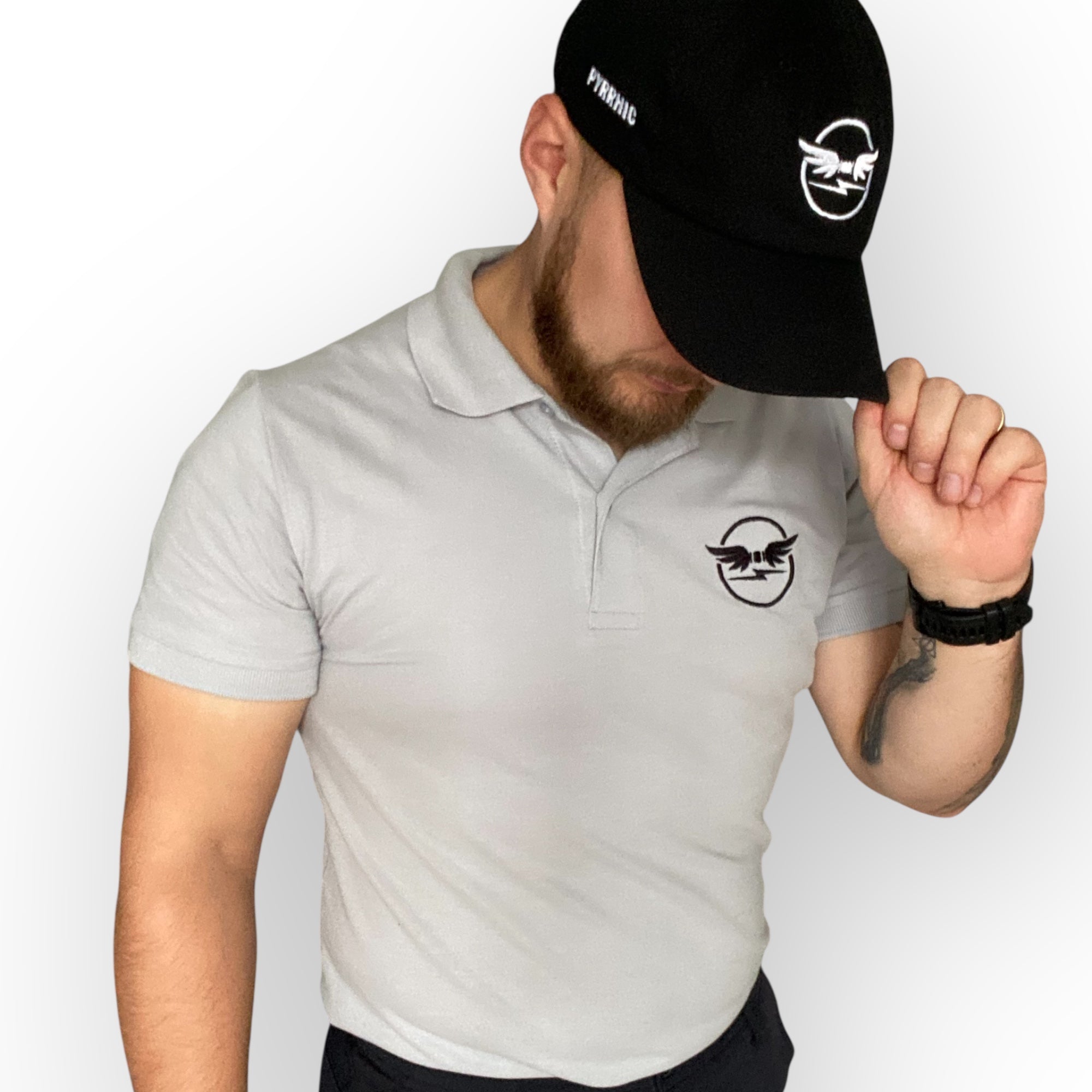 Man wearing a black pyrrhic wingmark cap and a light grey pyrrhic classic polo shirt with the pyrrhic logo on a white background